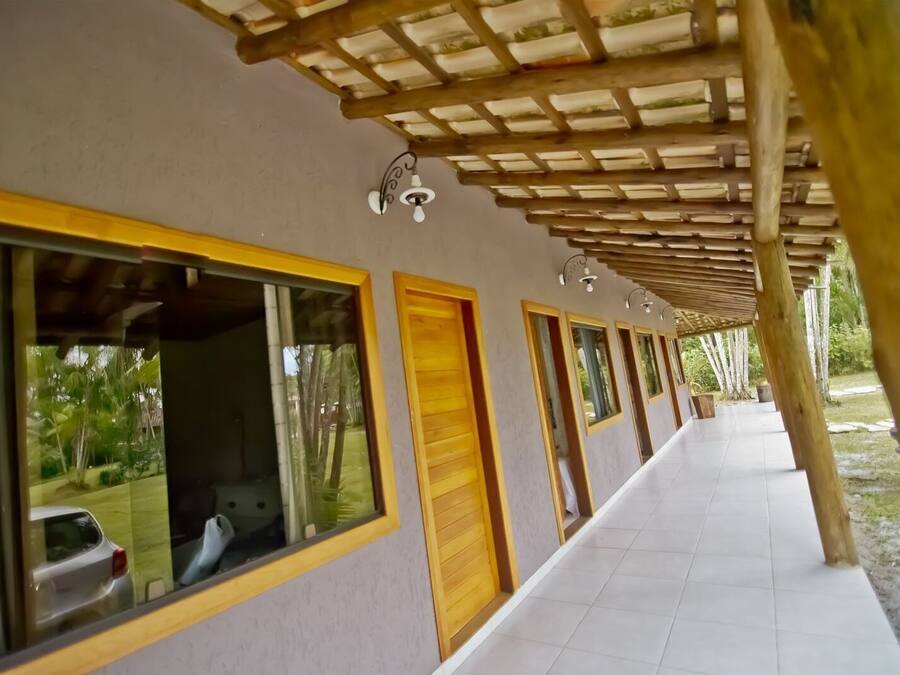 Un pasillo con ventanas amplias, puertas de madera y suelo de baldosas.