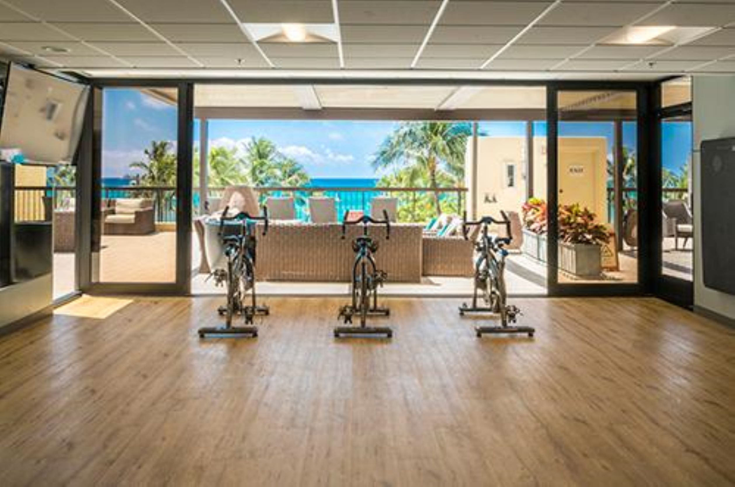Une salle de sport intérieure équipée de vélos d’exercice et offrant une vue sur l’océan.