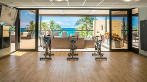 An indoor gym with exercise bikes and a view of the ocean.