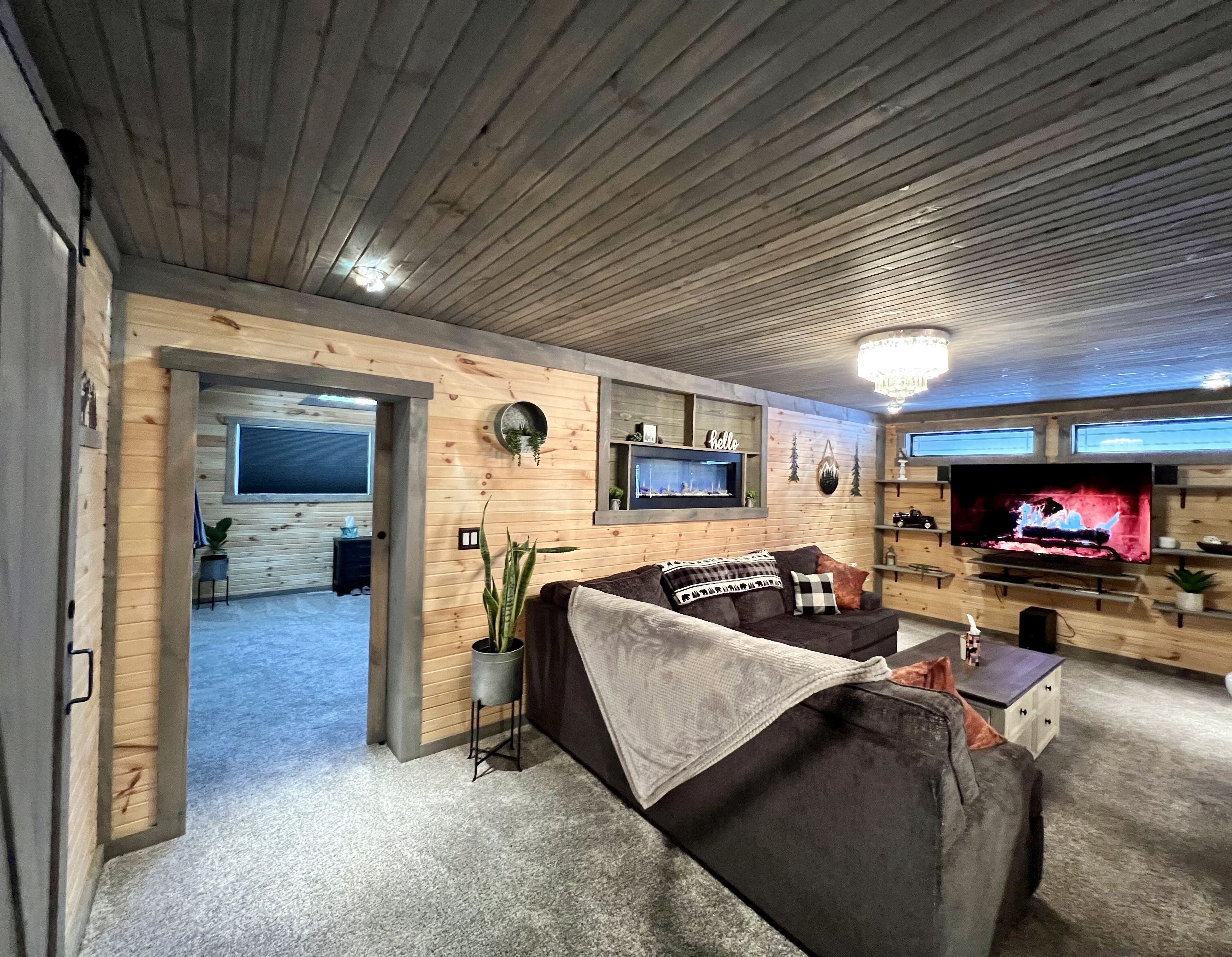 Una sala de estar acogedora con techo de madera, chimenea, televisor y sofá.
