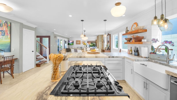 Een moderne keuken met een centraal eiland, witte kasten en hanglampen.