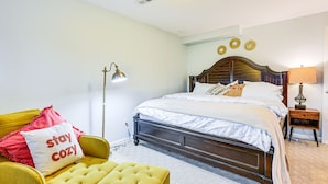 A bedroom with a bed, a yellow armchair, a lamp, and a bedside table.
