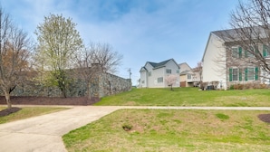 A residential area with houses, a stone wall, and a grassy lawn.