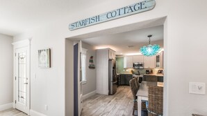 A modern kitchen with white cabinets, a stainless steel refrigerator, and a hanging light fixture.