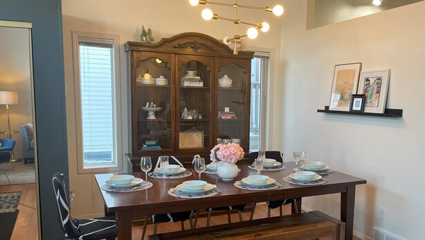 A dining room with a wooden table set for four, a bench, and a cabinet with glass doors. - Family Friendly, Gated Yard for Pets, Outdoor Firepit! (Calgary)