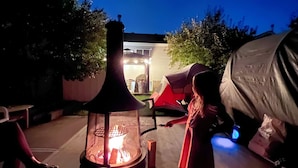 A patio with a fire pit, a tent, and a covered area. - Family Friendly, Gated Yard for Pets, Outdoor Firepit! (Calgary)