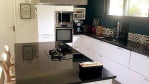 Una cocina moderna con armarios blancos, encimera negra y electrodomésticos de acero inoxidable, incluyendo un microondas y un horno.