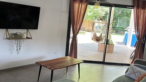 Una sala de estar con un sofá verde, una mesa de centro de madera y un televisor de pantalla plana montado en la pared.