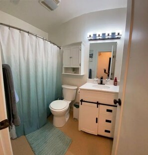 A bathroom with a shower curtain, toilet, sink, and cabinet. - Hillside 2 Bedroom Apartment In Portland (Portland)