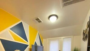 A living room with a sofa, a TV stand, and a geometric wall design. - Sky in Portland Studio-Apartment across from OHSU (Portland)