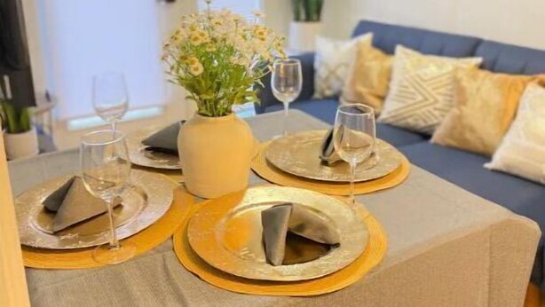 A dining area with a table set for two, a vase of flowers, and a sofa in the background. - Sky in Portland Studio-Apartment across from OHSU (Portland)