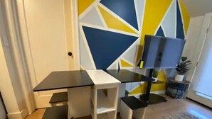 A room with a white desk, a black TV stand, and a geometric patterned wall. - Sky in Portland Studio-Apartment across from OHSU (Portland)
