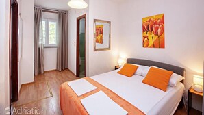Ein Hotelzimmer mit Bett, Nachttisch, Gemälde und einem Fenster mit Vorhängen.