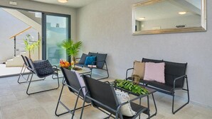 Ein modernes Wohnzimmer mit Glastür, die auf einen Balkon führt, einem großen Spiegel und einem Couchtisch mit Dekoration.