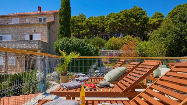 A rooftop terrace with wooden loungers, towels, a bottle, and a magazine. - Palm Tree Apartments - A8 (Dubrovnik)