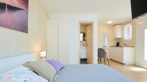 A bedroom with a bed, a nightstand, and a painting on the wall. - Palm Tree Apartments - A8 (Dubrovnik)