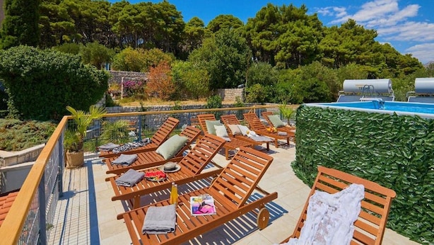 A rooftop pool area with wooden loungers and a small pool.