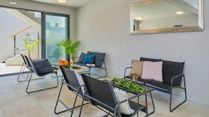 A modern living room with a glass door leading to a balcony, a large mirror, and a coffee table with decorative items.