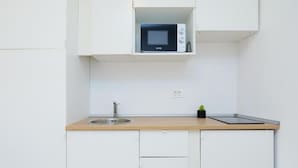 A compact kitchen with a microwave, sink, and a small potted plant.