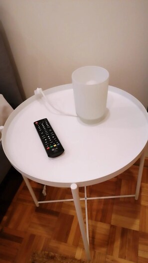 A small round table with a white tablecloth, a remote control, and a white cup on top. - Porto Brasil Hostel (Porto)