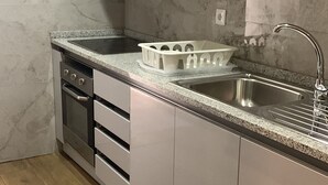 A modern kitchen with stainless steel appliances, a granite countertop, and a built-in sink. - Porto Brasil Hostel (Porto)