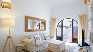 A living room with a sofa, ottoman, lamp, and a desk with a computer. - Casa Carbo, Air Conditioning - Puerto del Carmen, Lanzarote (Puerto del Carmen)