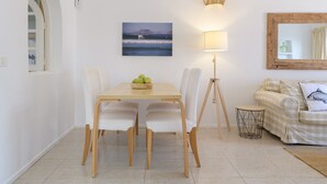 A dining area with a table and chairs, a lamp, a framed picture, and a sofa with a cushion. - Casa Carbo, Air Conditioning - Puerto del Carmen, Lanzarote (Puerto del Carmen)
