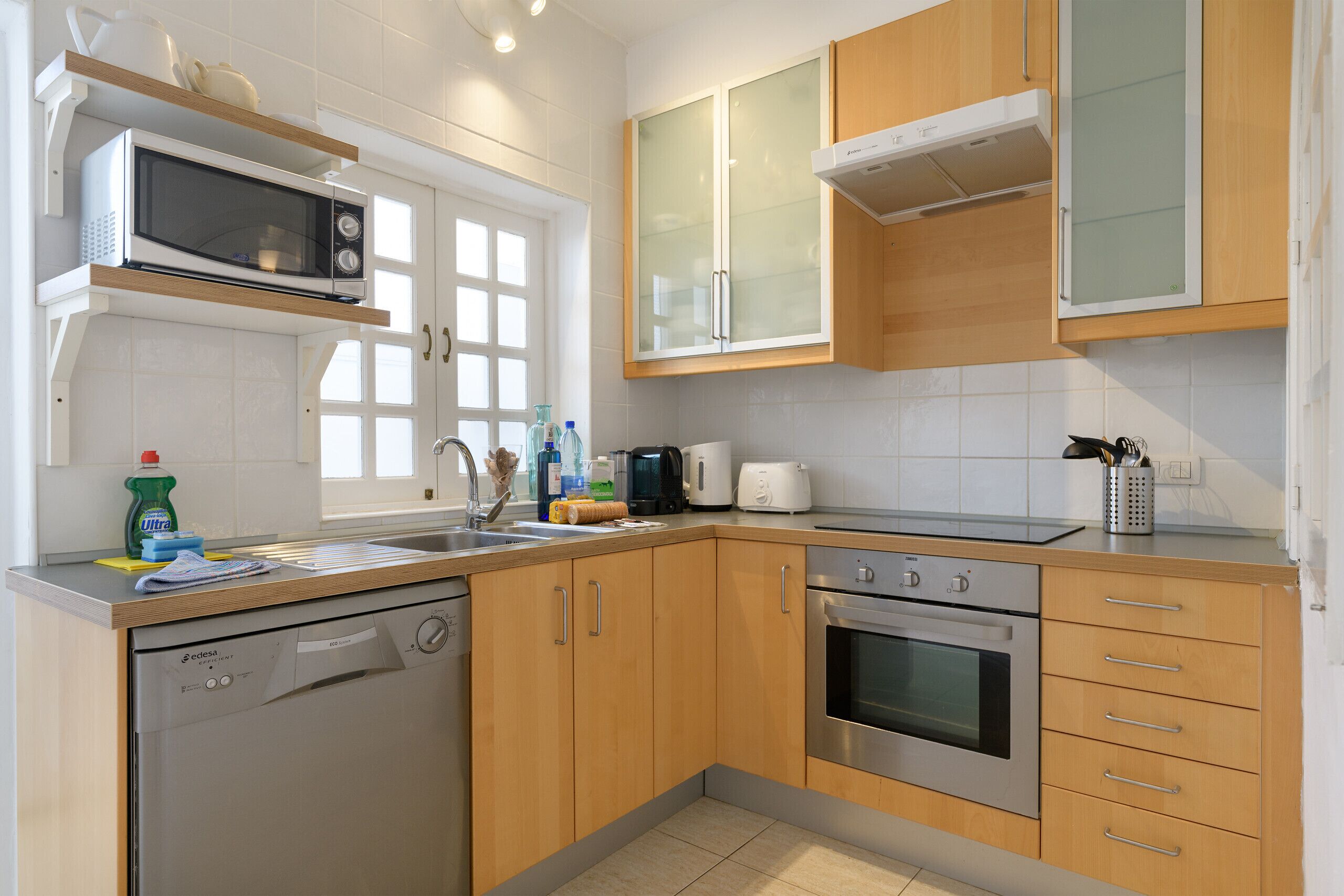 Une cuisine moderne dotée de meubles en bois, d’un lave-vaisselle, d’un four à micro-ondes, d’un grille-pain et d’un évier.
