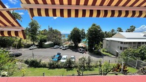 A view of a parking area with several cars, a building with a white roof, and a clear blue sky. - Studio Hibiscus n°2 with sea and mountain views, beach access, + cistern (Le Gosier)