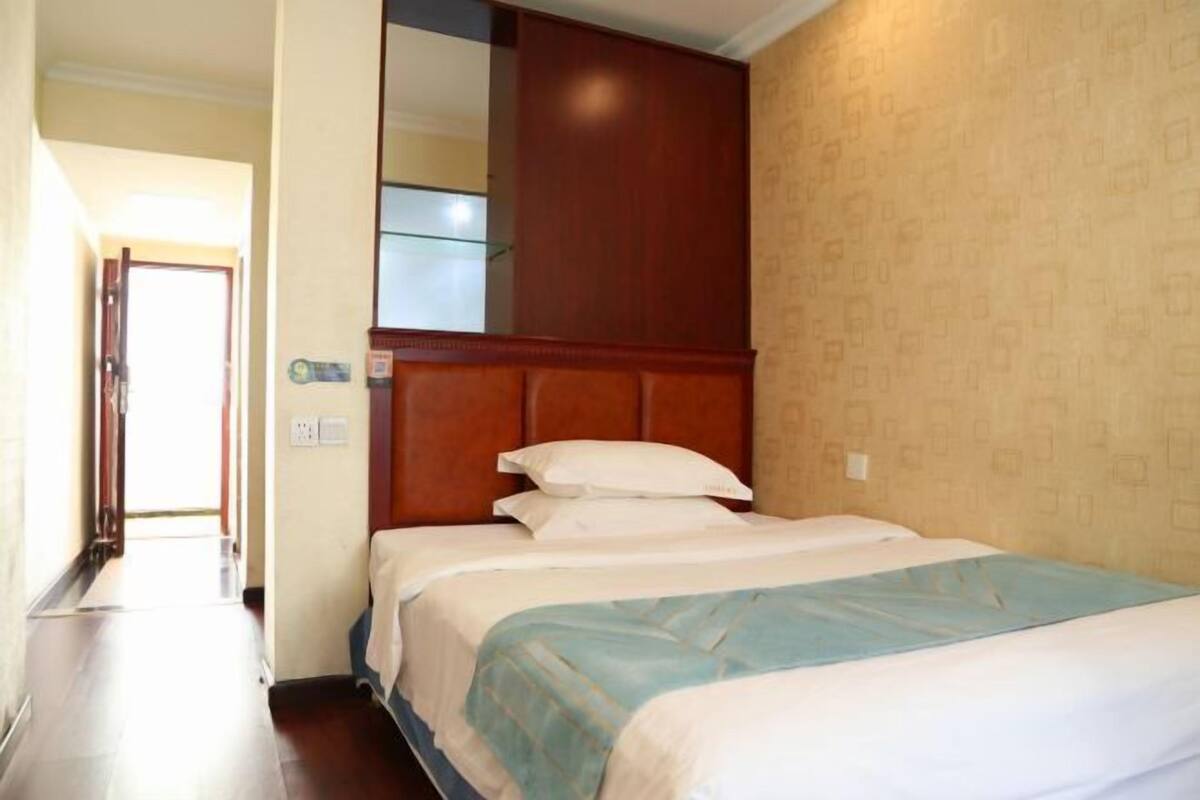 Une chambre d’hôtel avec un grand lit, une tête de lit en bois et un miroir au-dessus du lit.