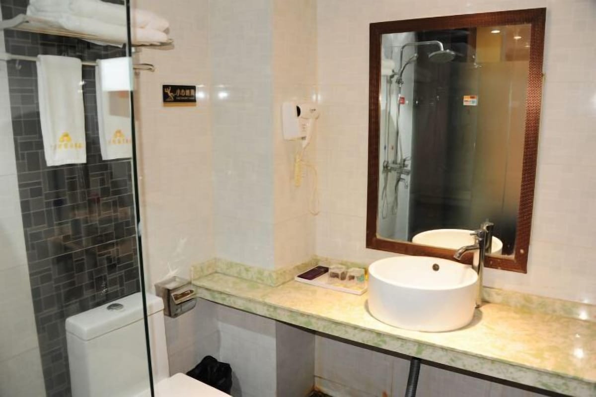 Un baño con cabina de ducha de vidrio, un lavabo blanco y un espejo.