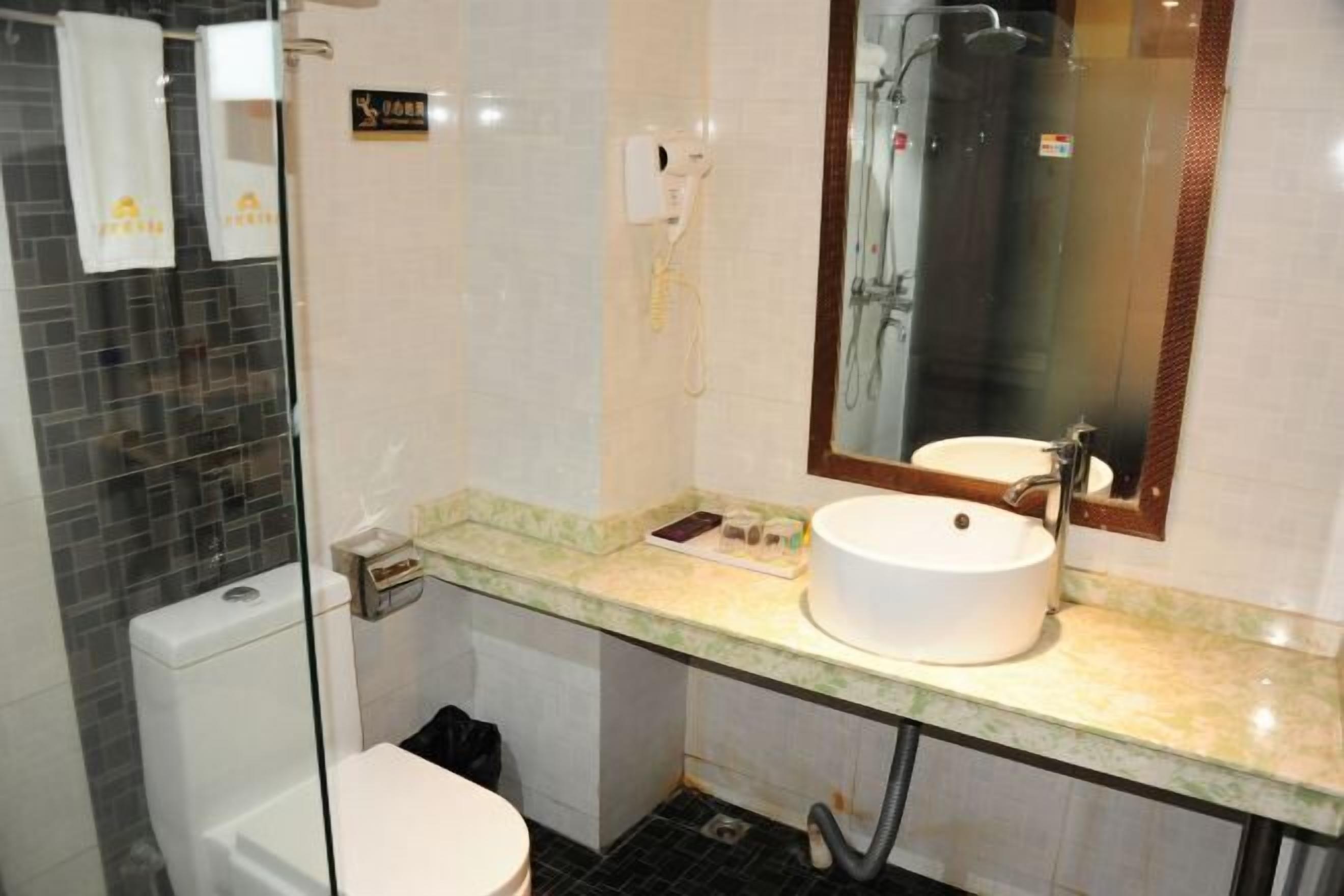 A bathroom with a glass shower enclosure, a toilet, a sink with a mirror, and a towel rack.