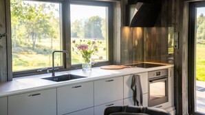 A modern kitchen with a large window, a sink, a cutting board, and an oven.