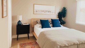 A bedroom with a bed, bedside table, lamp, framed picture, and a ceiling fan. - Back Unit · Beach House in the <3 of Balboa Peninsula (Newport Beach)
