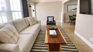 A living room with a sofa, a coffee table, a TV, and a dining area. - Back Unit · Beach House in the <3 of Balboa Peninsula (Newport Beach)