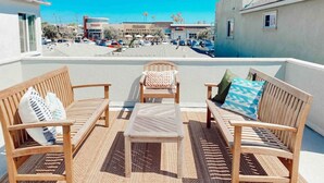 A rooftop terrace with wooden furniture and a view of a parking lot and buildings. - Back Unit · Beach House in the <3 of Balboa Peninsula (Newport Beach)
