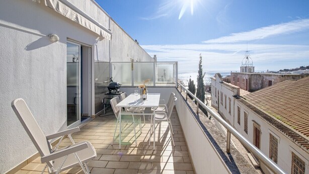 En balkon med et bord, stole og grill.