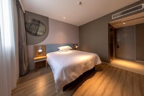 A modern hotel room with a large bed, bedside lamps, a wall-mounted circular light fixture, and a door to a bathroom. - Homeinn Hotel (Yangzhou University Grand Canal Museum) (Yangzhou)
