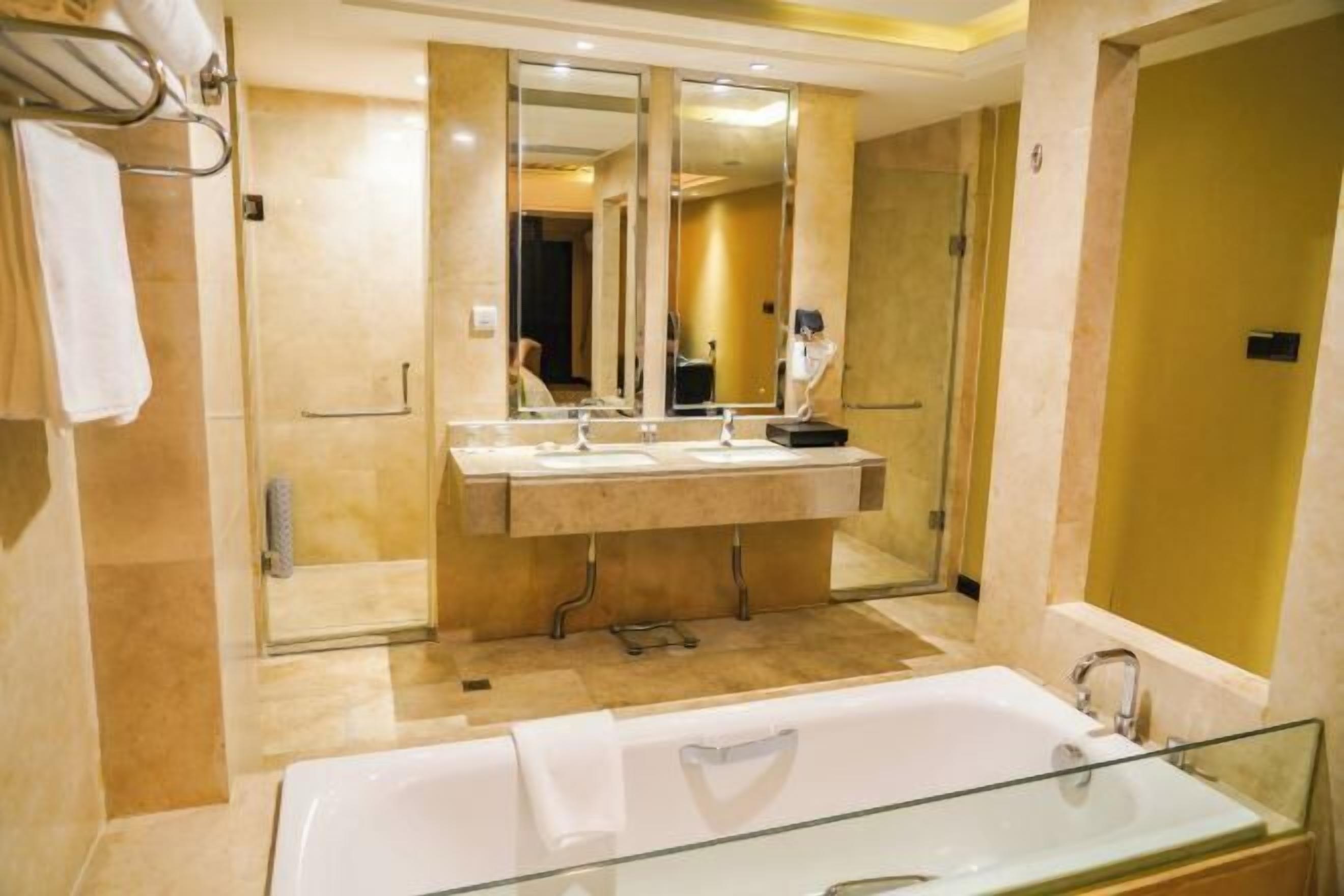 Ein modernes Badezimmer mit einer gläsernen Duschkabine, einem großen Spiegel über einem Waschtisch mit zwei Becken und einer freistehenden Badewanne.