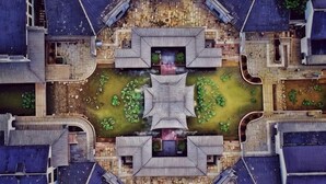 A symmetrical courtyard with a central water feature, surrounded by traditional buildings with tiled roofs. - Metropark Longhua Hotel (Xinyu)