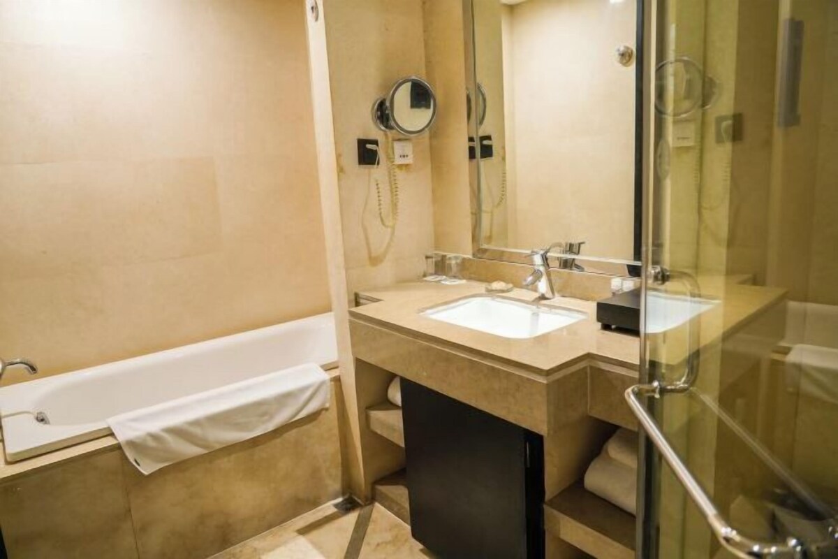 A bathroom with a bathtub, two sinks, a mirror, and a glass shower enclosure.