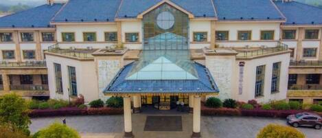 Un grand bâtiment doté d’une façade centrale en verre et d’une toiture à symétrie parfaite.