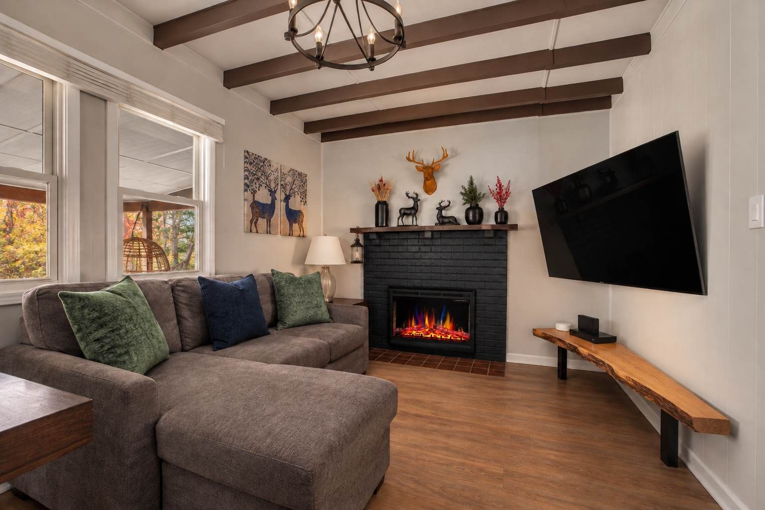 A living room with a sectional sofa, a fireplace, a mounted TV, and a wooden bench.