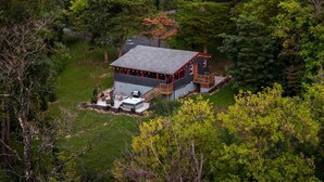 A cabin with a deck, surrounded by dense forest.