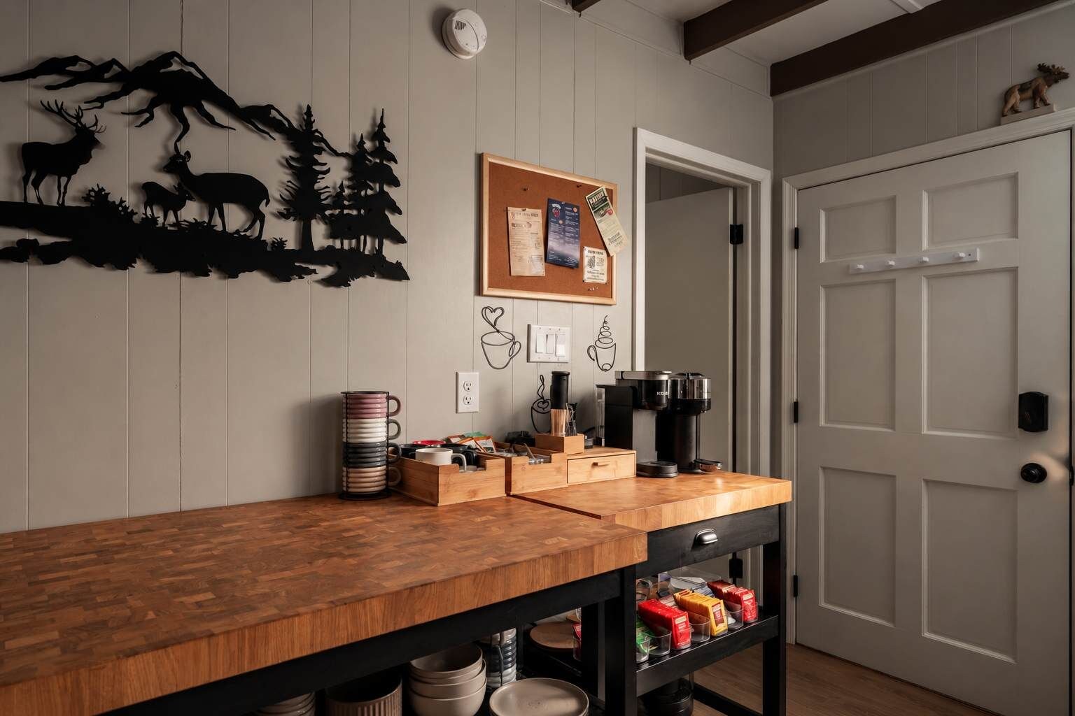 A kitchen area with a wooden countertop, a coffee machine, and a corkboard with notes.
