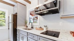 A modern kitchen with stainless steel appliances, a double sink, and a window overlooking greenery.