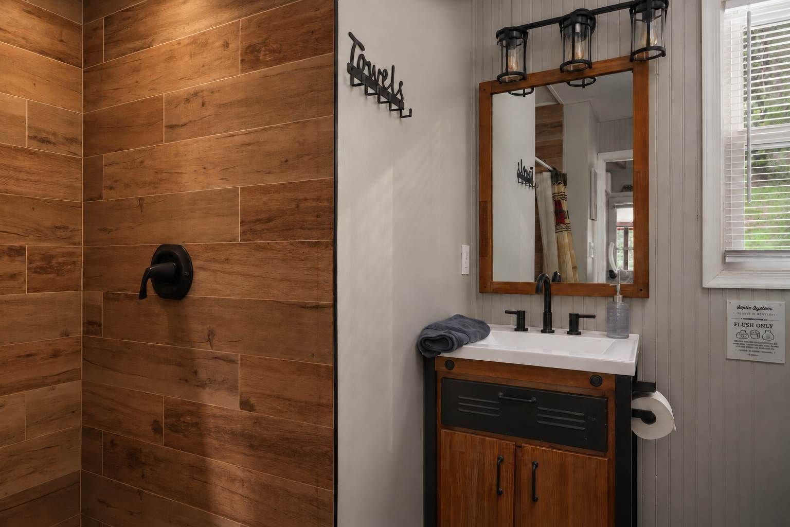 From the doorway, the walk-in shower and vanity sit side by side, with hooks ready for towels.