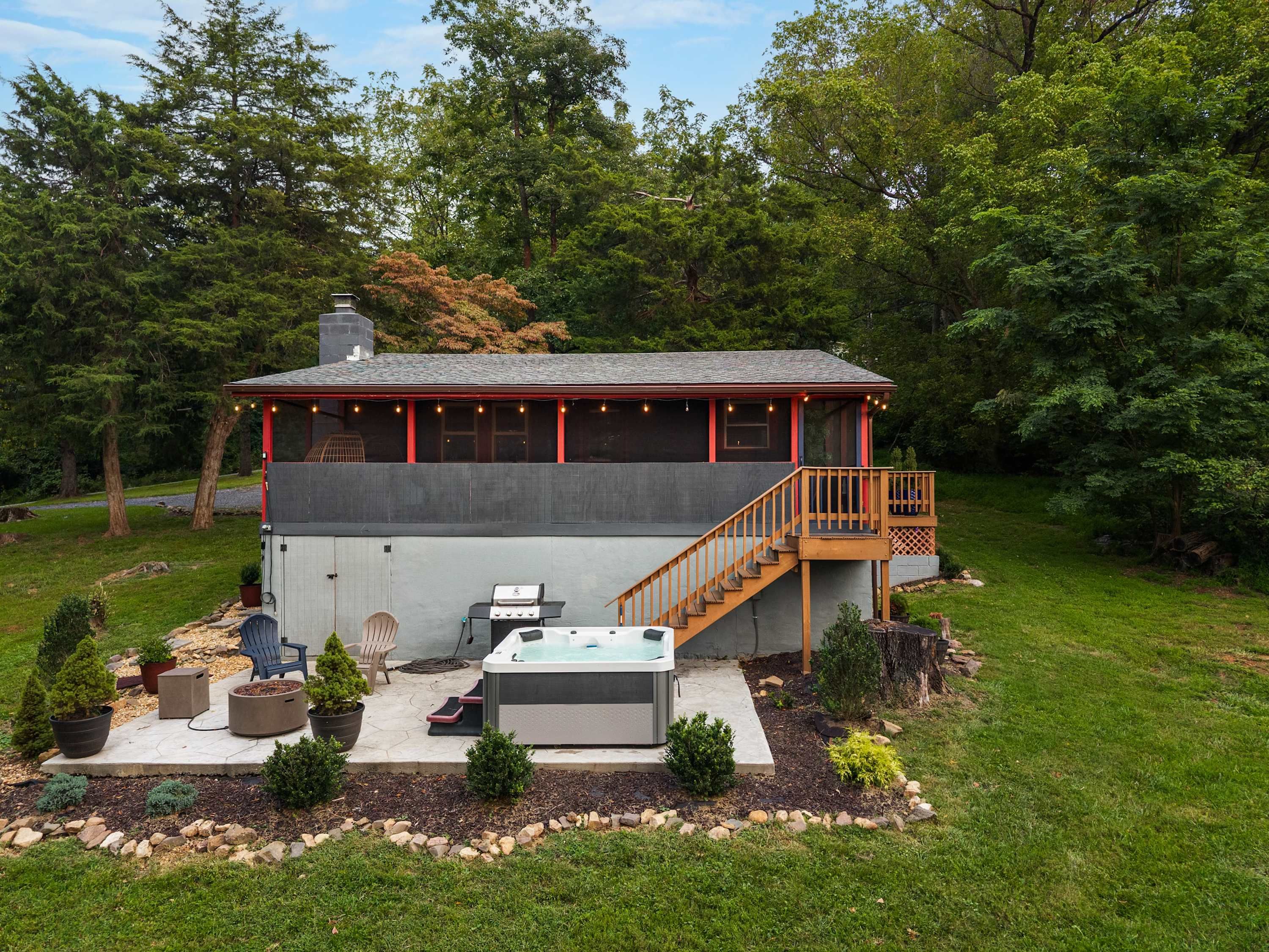 Ein zweistöckiges Haus mit überdachter Terrasse, einem Whirlpool im Freien und einer Treppe, die zu einer Außenterrasse führt.