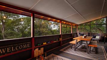 A cozy outdoor seating area with a 'WELCOME' sign, wooden furniture, and a patterned rug.