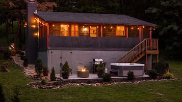 A modern house with a covered patio, outdoor seating, and a fireplace.